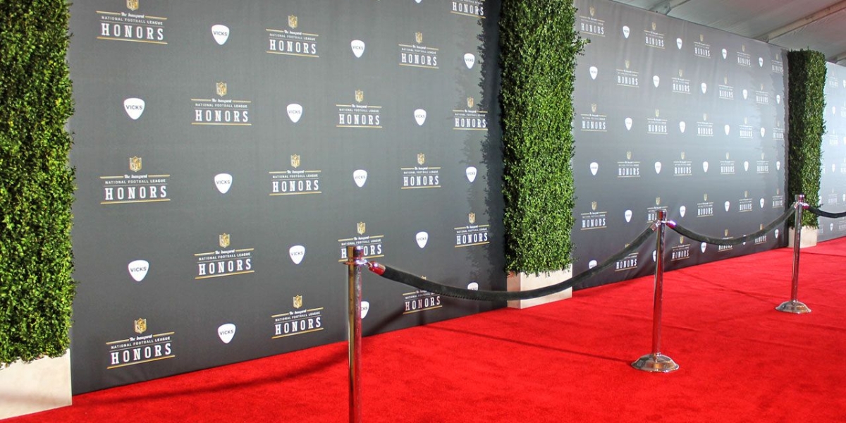 Branded backdrops for events displayed on a red carpet setup featuring NFL Honors logos with green ivy accents and professional event barriers.