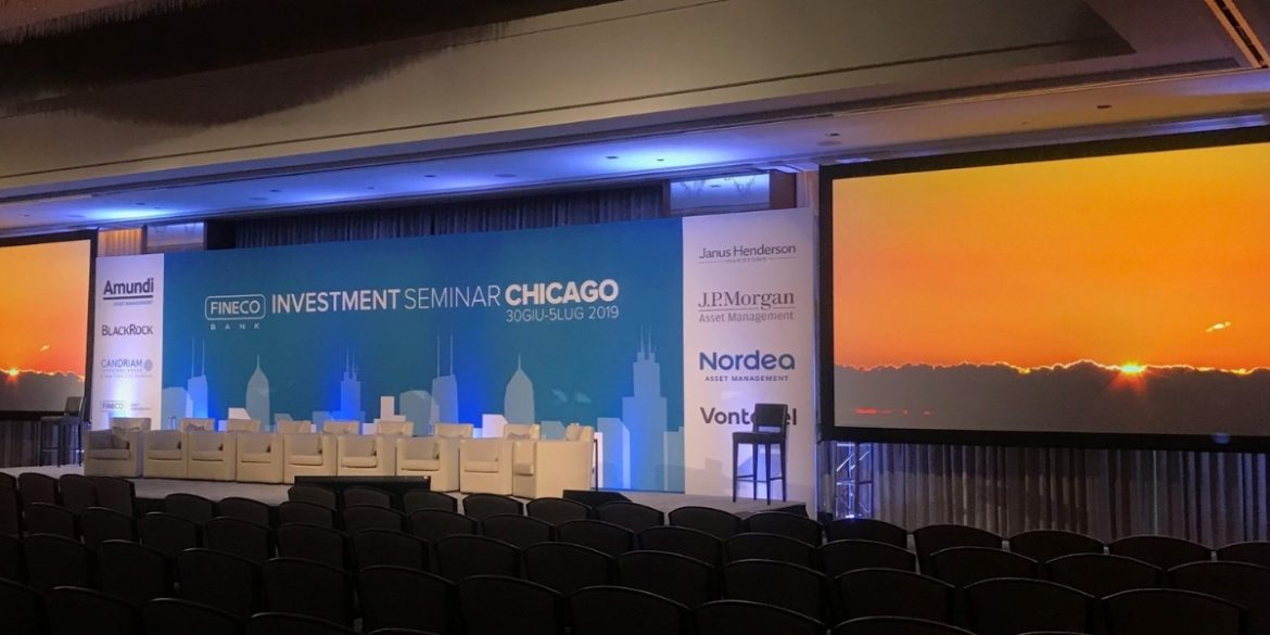Branded backdrops for events displayed at a FINECO Investment Seminar in Chicago featuring company logos and a skyline backdrop with professional stage setup.